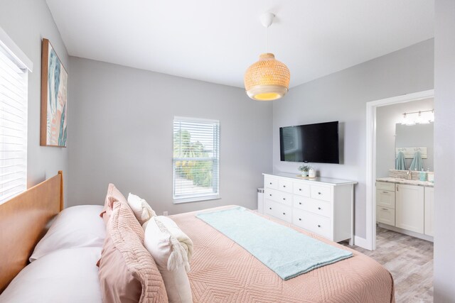 bedroom featuring ensuite bath and light hardwood / wood-style floors