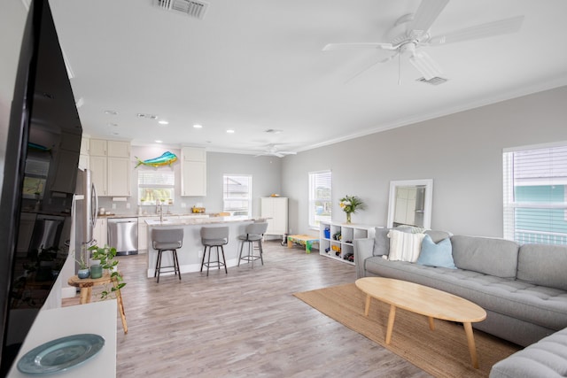 living room featuring ceiling fan, ornamental molding, and light hardwood / wood-style floors