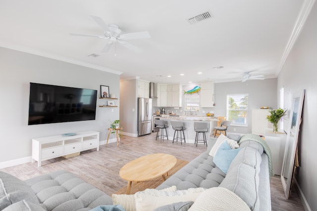 living room with crown molding, ceiling fan, and light hardwood / wood-style floors