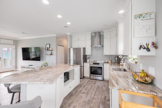 kitchen featuring wall chimney range hood, sink, appliances with stainless steel finishes, a center island, and light stone countertops