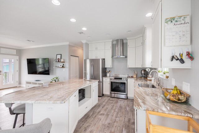 kitchen featuring wall chimney range hood, sink, appliances with stainless steel finishes, a center island, and light stone countertops