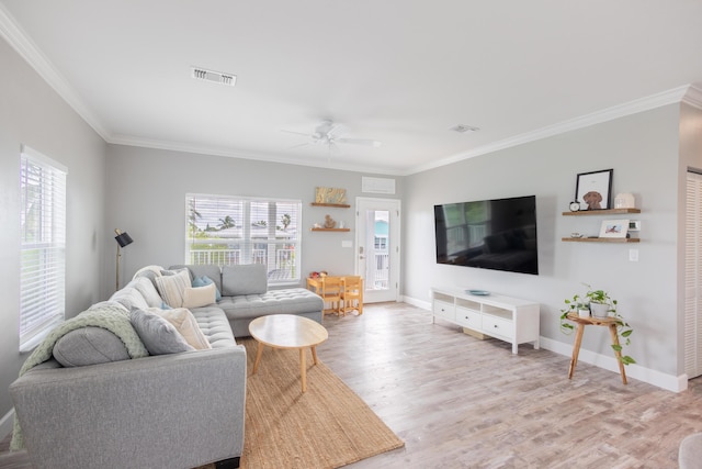 living room featuring plenty of natural light, ornamental molding, and light wood-type flooring