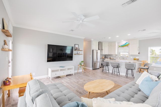 living room with ceiling fan, ornamental molding, and light wood-type flooring