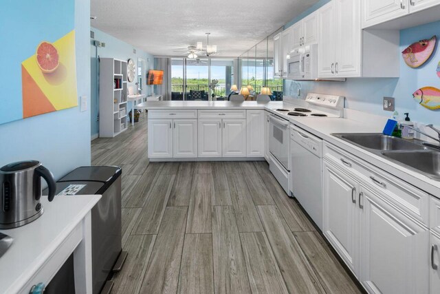 kitchen with sink, white appliances, white cabinetry, a textured ceiling, and kitchen peninsula