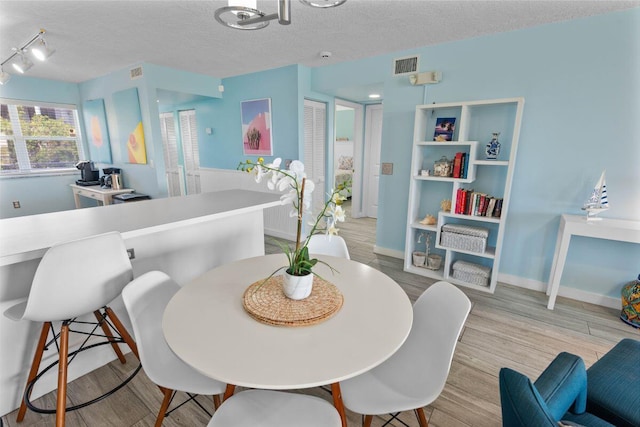 dining space featuring a textured ceiling and light hardwood / wood-style floors