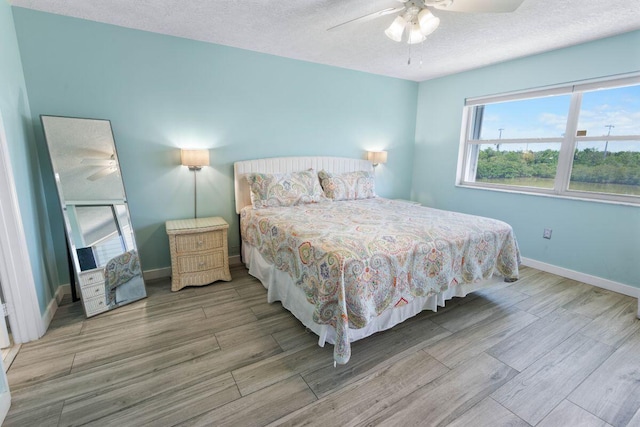 bedroom featuring ceiling fan, hardwood / wood-style flooring, and a textured ceiling