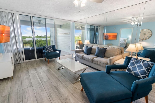 living room featuring expansive windows, ceiling fan, a textured ceiling, and light hardwood / wood-style flooring