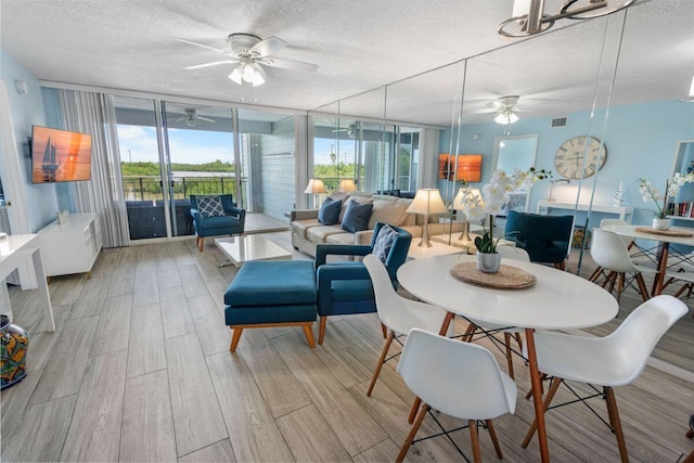 dining space with expansive windows, a textured ceiling, and light hardwood / wood-style flooring