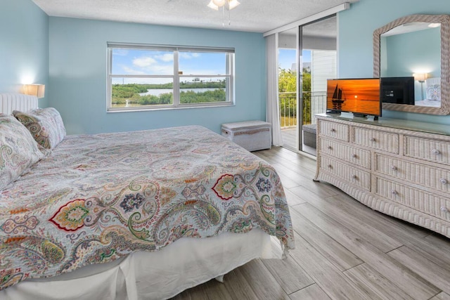 bedroom featuring hardwood / wood-style flooring, access to exterior, and a textured ceiling