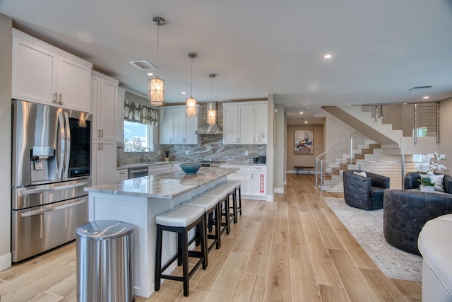 kitchen with white cabinetry, hanging light fixtures, stainless steel appliances, a center island, and light stone countertops