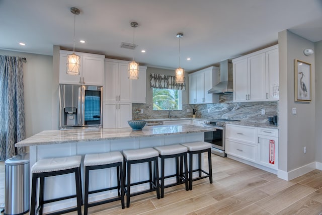 kitchen featuring white cabinetry, stainless steel appliances, wall chimney exhaust hood, and a center island