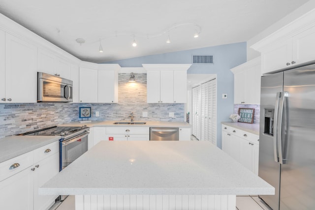 97 Coral Ln, Key Colony, FL 33051 - kitchen with stainless steel appliances, lofted ceiling, backsplash, a center island, and white cabinets
