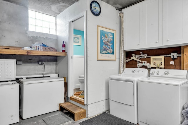 clothes washing area featuring cabinets and separate washer and dryer