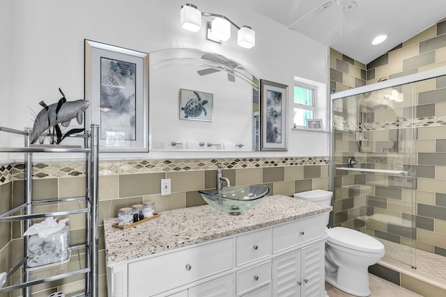 bathroom with lofted ceiling, tile walls, vanity, a shower with shower door, and toilet