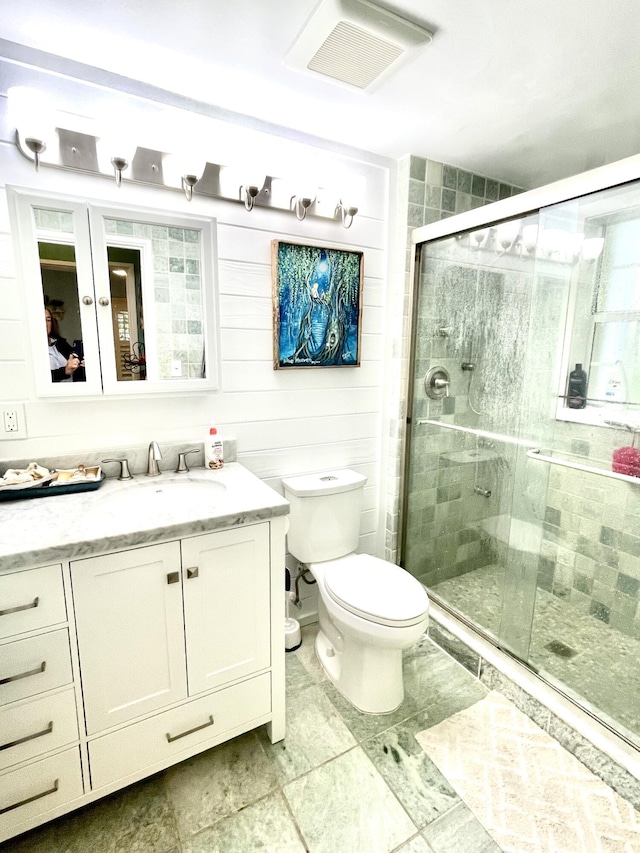 full bathroom with vanity, a shower stall, toilet, and visible vents