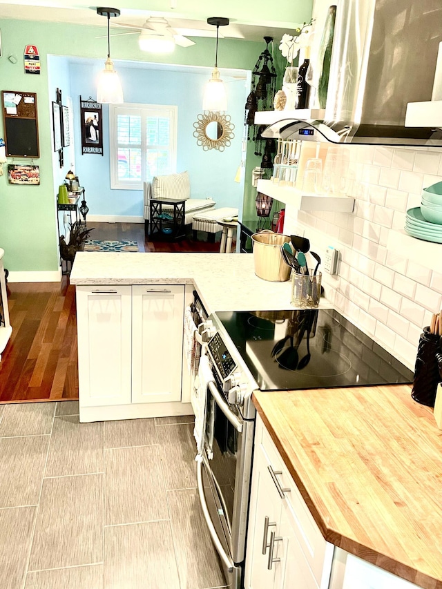 kitchen with backsplash, decorative light fixtures, electric stove, wood counters, and white cabinetry