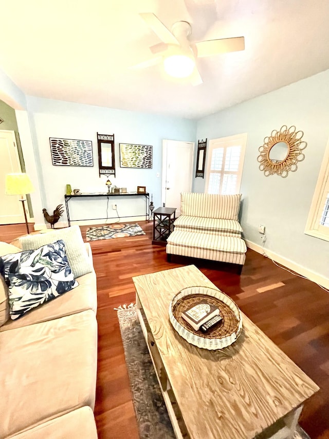 living area featuring baseboards, a ceiling fan, and wood finished floors