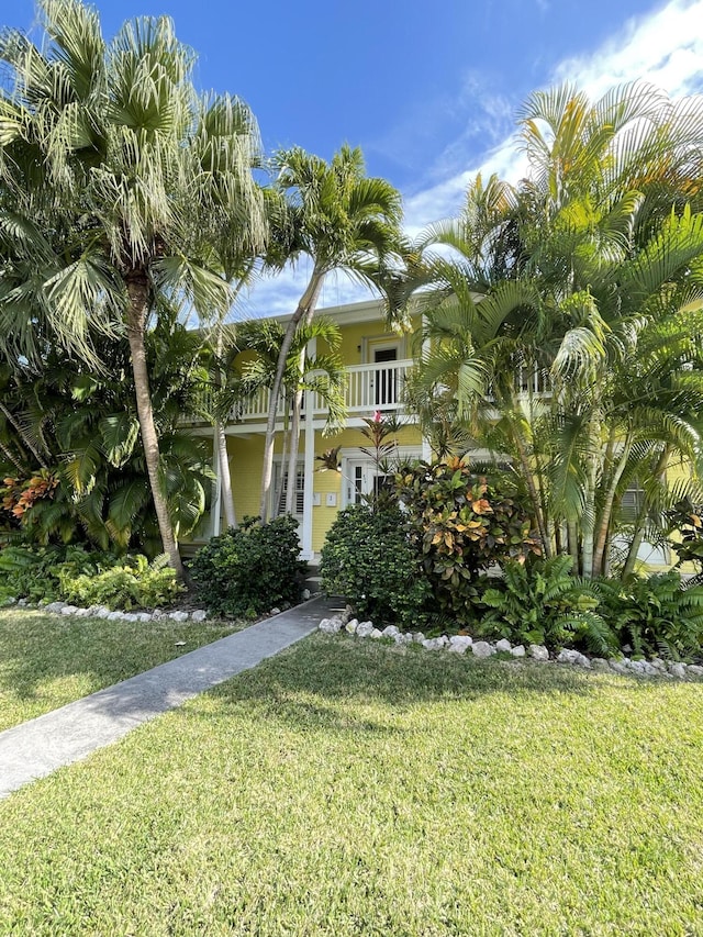 obstructed view of property with a balcony, stucco siding, french doors, and a front yard