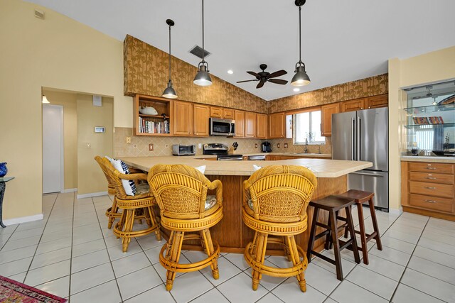 kitchen with light tile patterned flooring, sink, vaulted ceiling, appliances with stainless steel finishes, and a kitchen breakfast bar