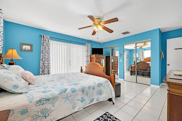 bedroom featuring multiple closets, light tile patterned flooring, and ceiling fan