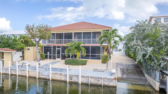 back of property with a water view and a sunroom