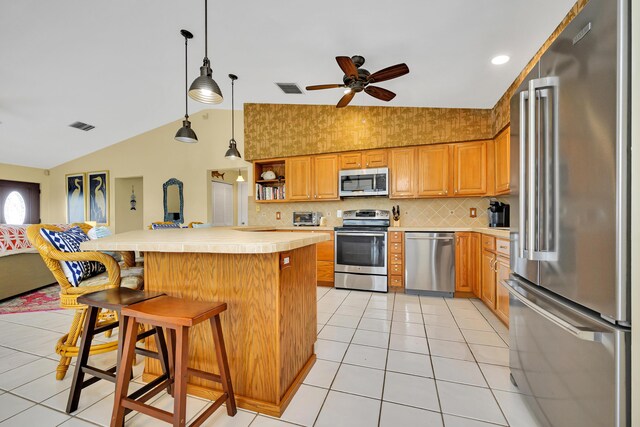 kitchen featuring light tile patterned flooring, a kitchen bar, vaulted ceiling, appliances with stainless steel finishes, and backsplash