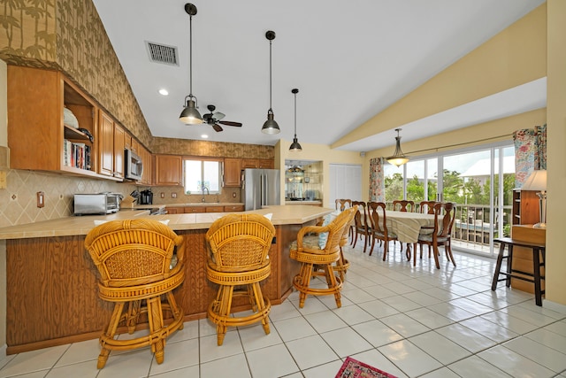 kitchen with vaulted ceiling, tasteful backsplash, a kitchen breakfast bar, kitchen peninsula, and stainless steel appliances