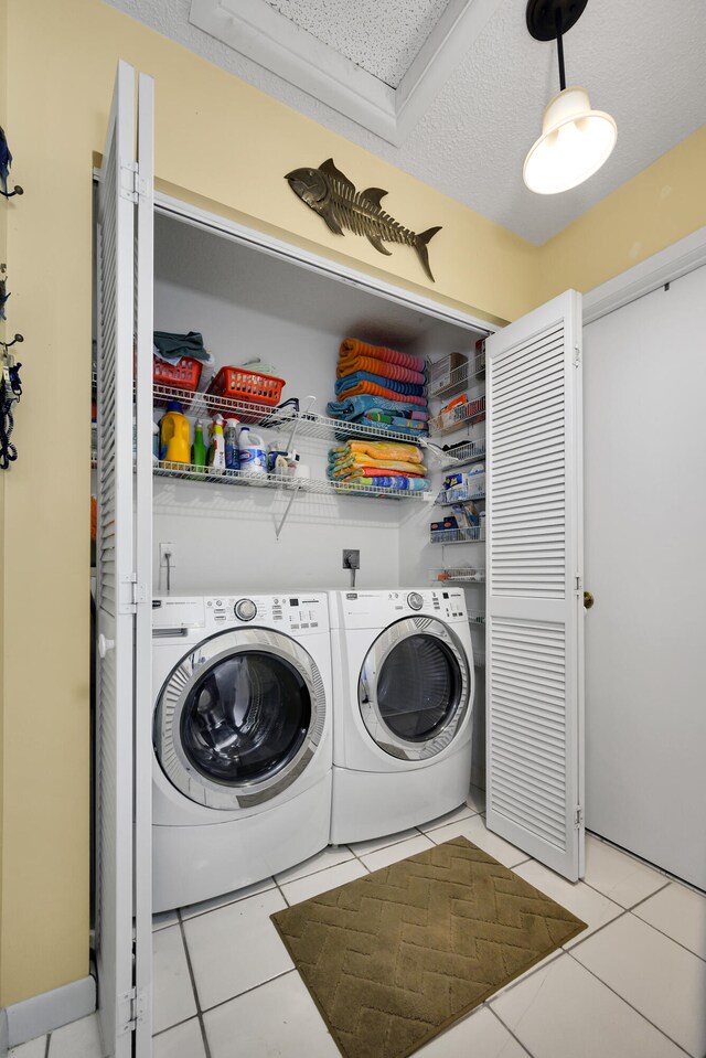 laundry room with light tile patterned floors, washer and clothes dryer, and a textured ceiling