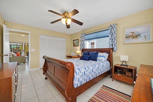 bedroom featuring ceiling fan, a textured ceiling, a closet, and light tile patterned floors