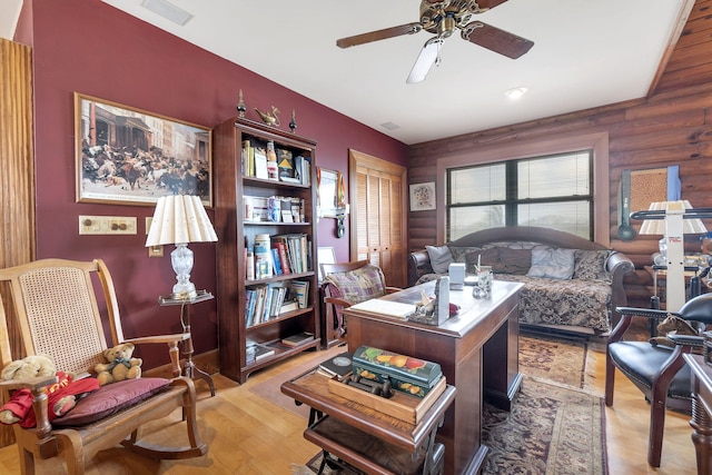 office with ceiling fan, rustic walls, and light hardwood / wood-style flooring