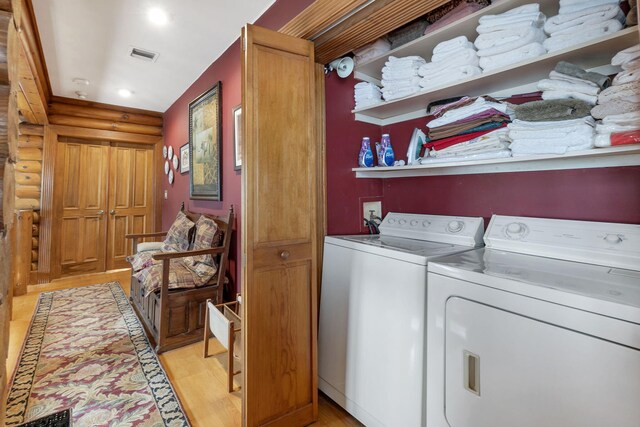 washroom with separate washer and dryer, log walls, and light hardwood / wood-style flooring