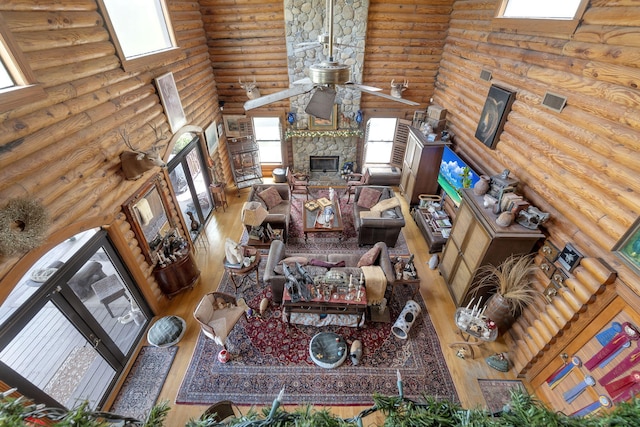 living room featuring hardwood / wood-style flooring, ceiling fan, a towering ceiling, and a fireplace