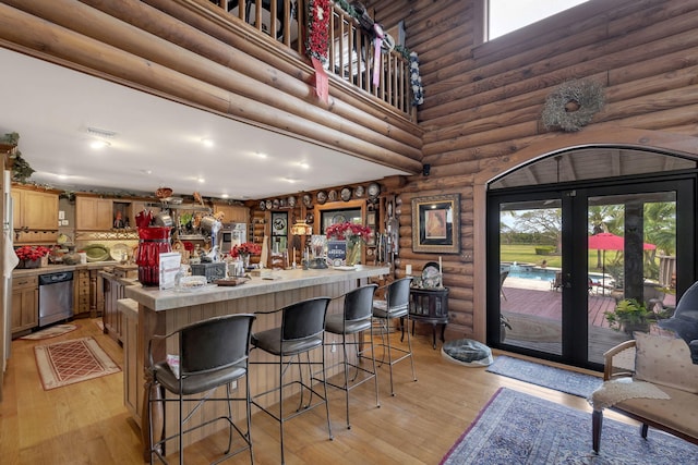 kitchen with a wealth of natural light, dishwasher, light hardwood / wood-style floors, and a high ceiling