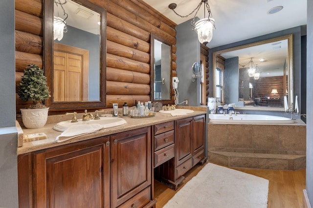 bathroom with vanity, tiled tub, log walls, and wood-type flooring