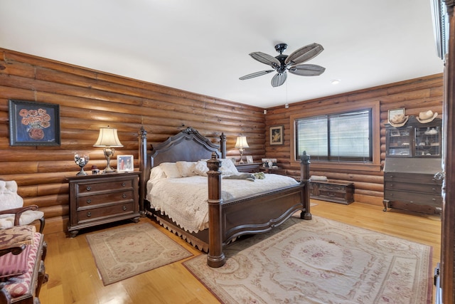 bedroom featuring ceiling fan, log walls, and light hardwood / wood-style floors