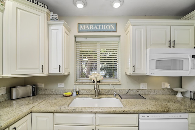 kitchen with sink, light stone counters, white cabinets, and white appliances