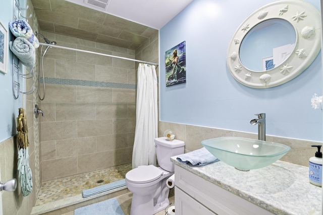 bathroom with vanity, curtained shower, tile walls, and toilet