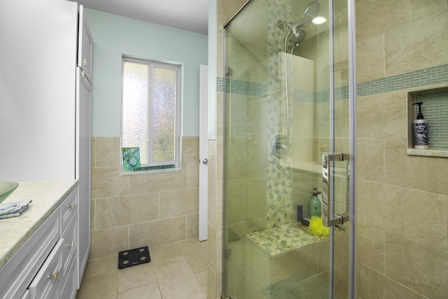 bathroom with vanity, a shower with shower door, and tile walls