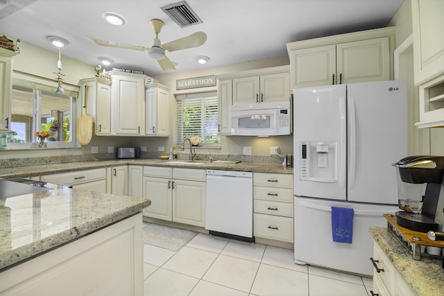 kitchen with sink, white appliances, light tile patterned floors, ceiling fan, and light stone counters