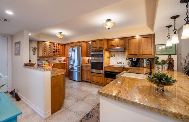 kitchen featuring pendant lighting, sink, appliances with stainless steel finishes, light stone countertops, and kitchen peninsula