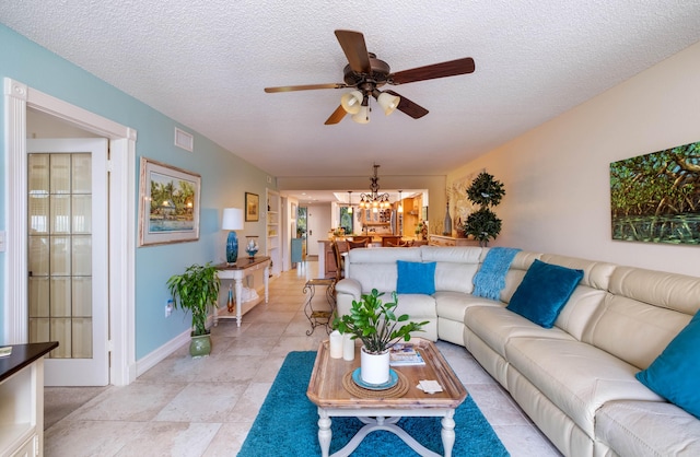 living room featuring ceiling fan with notable chandelier and a textured ceiling