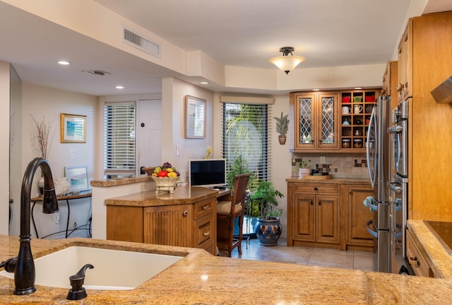 kitchen featuring light tile patterned flooring, stainless steel refrigerator, sink, backsplash, and kitchen peninsula