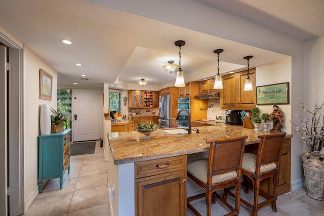 kitchen featuring sink, a kitchen breakfast bar, kitchen peninsula, pendant lighting, and stainless steel appliances