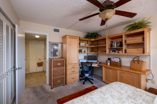 bedroom featuring light carpet, built in desk, and a textured ceiling