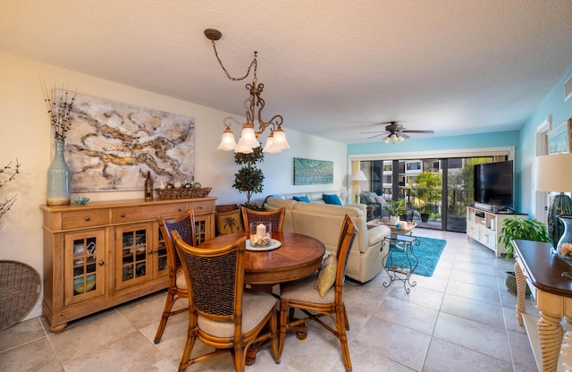 tiled dining space featuring ceiling fan with notable chandelier and a textured ceiling