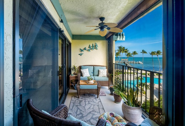 balcony featuring a water view, ceiling fan, and outdoor lounge area