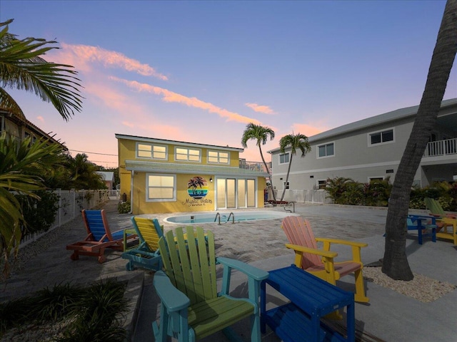 back house at dusk featuring a fenced in pool and a patio