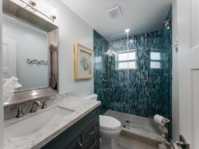 bathroom with vanity, toilet, and tiled shower