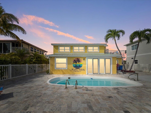 pool at dusk featuring a patio area