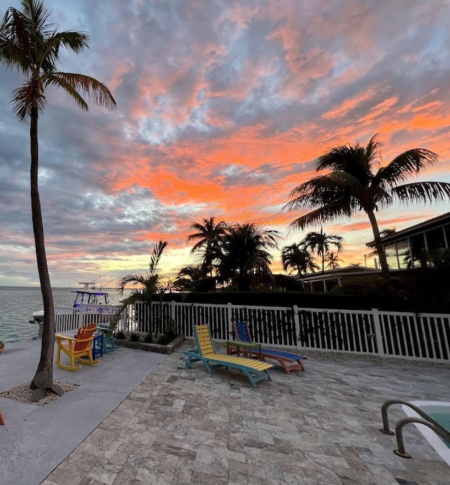 patio terrace at dusk featuring a water view